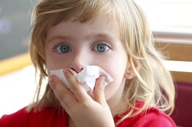 blond girl with tissues pressed to nose