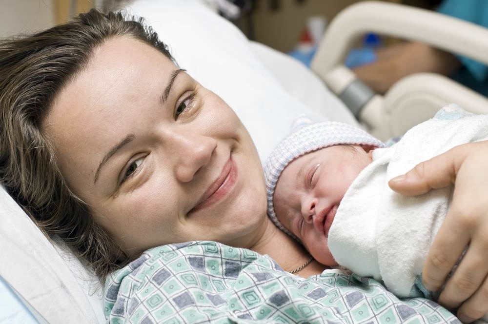 Happy mother with newborn baby in hospital bed