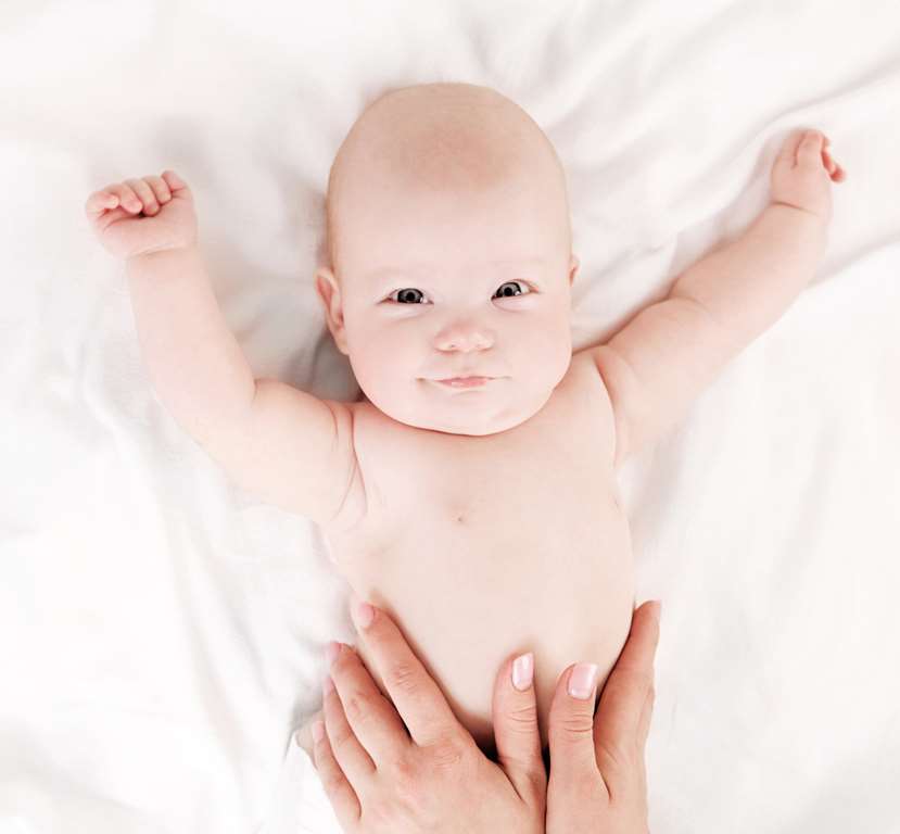 Happy baby being massaged with lotion