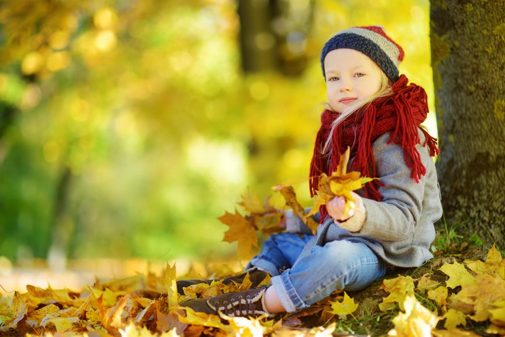 child playing outside in fall leaves