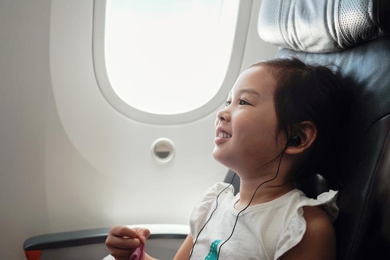 Young Asian girl watching movie in flight, family traveling abroad with children