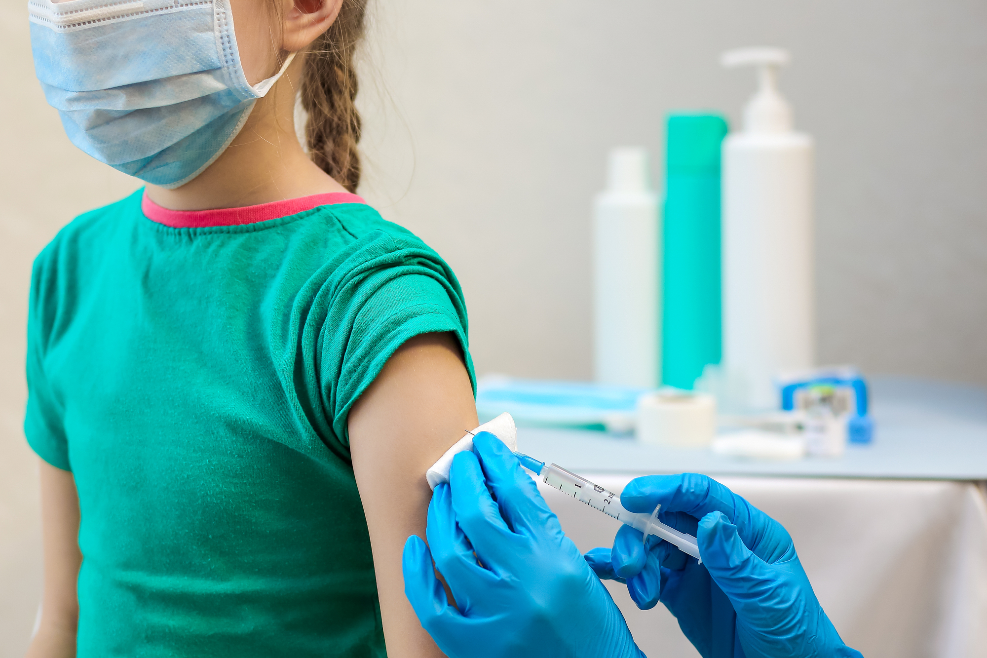 Child receiving a vaccine shot from a healthcare worker in blue gloves