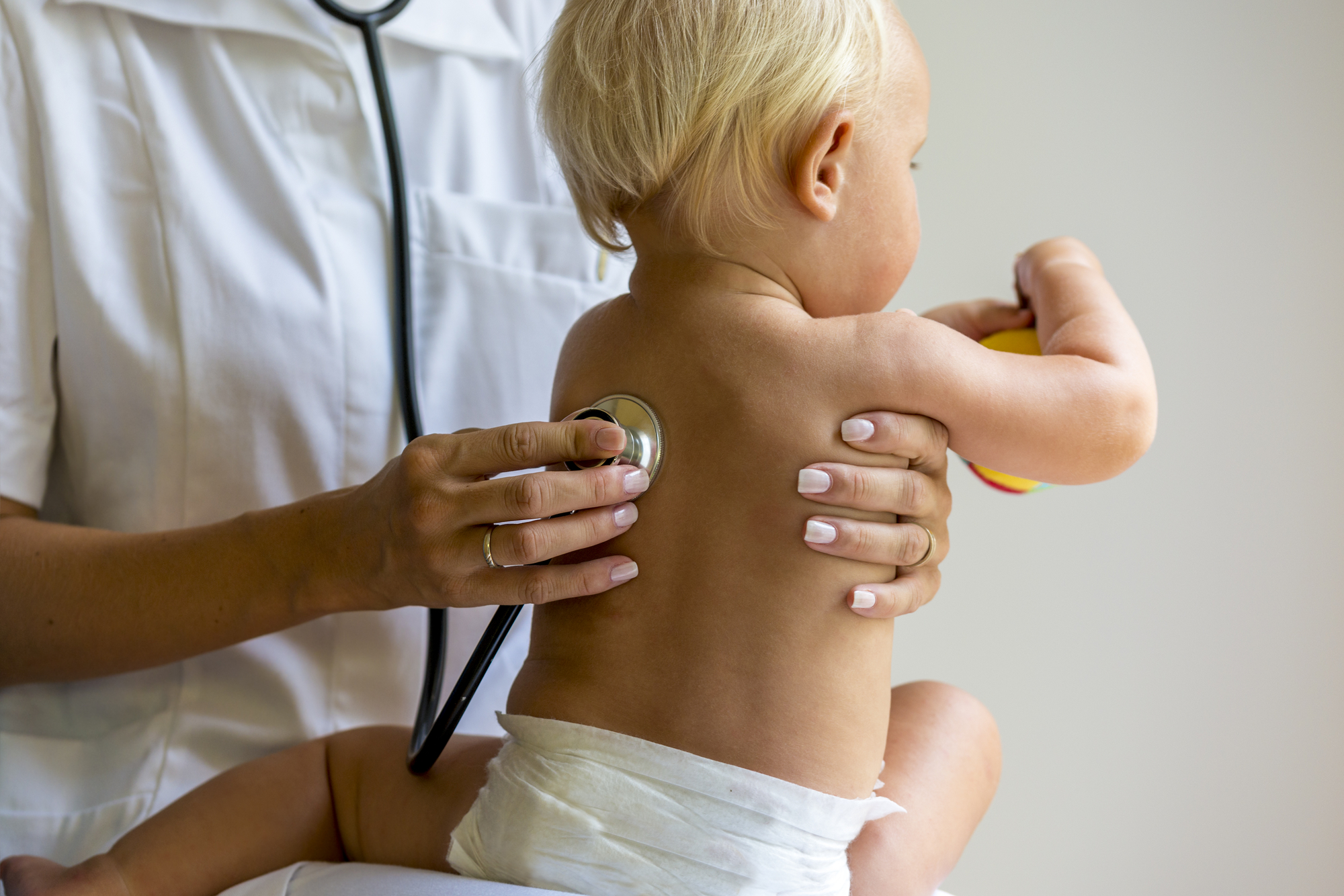 A Frisco healthcare professional auscultating a toddler's back with a stethoscope